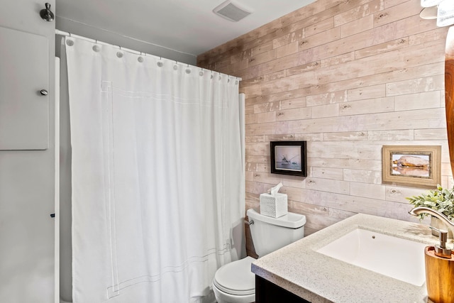 bathroom with wooden walls, vanity, a shower with curtain, and toilet