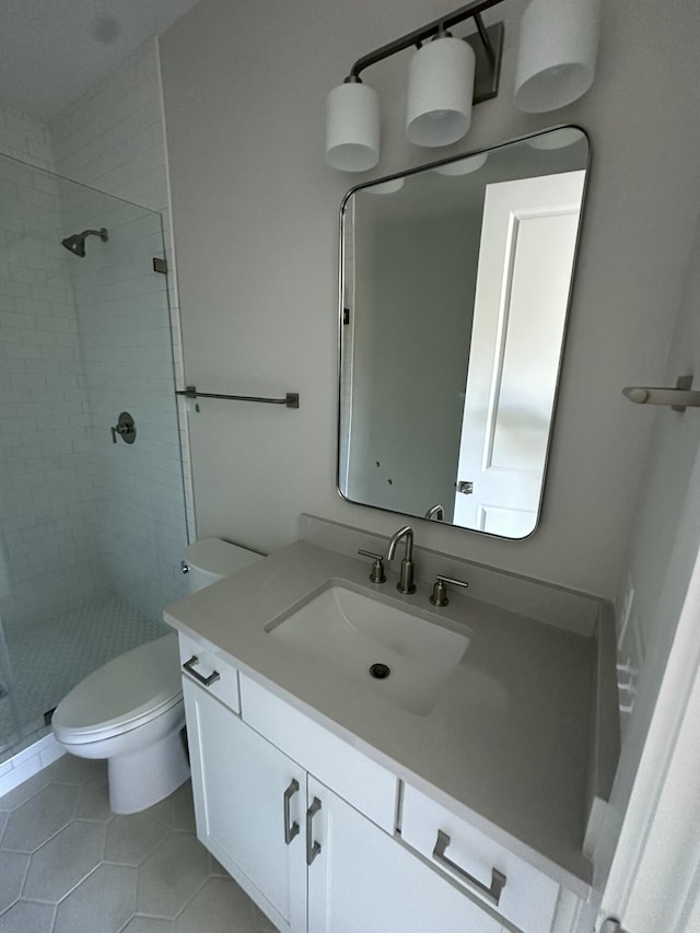 bathroom with vanity, a tile shower, tile patterned floors, and toilet