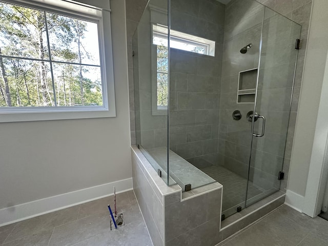 bathroom featuring tile patterned flooring, plenty of natural light, and a shower with door