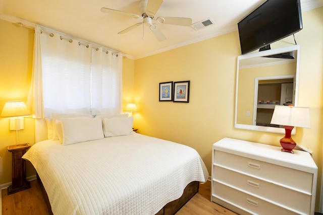 bedroom with visible vents, light wood-style floors, ornamental molding, and a ceiling fan