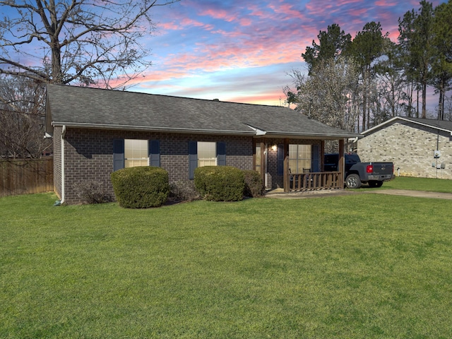 ranch-style home featuring a front lawn, a shingled roof, and brick siding