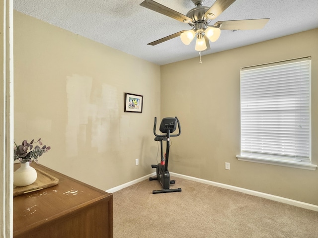 exercise room with a textured ceiling, carpet flooring, a ceiling fan, and baseboards