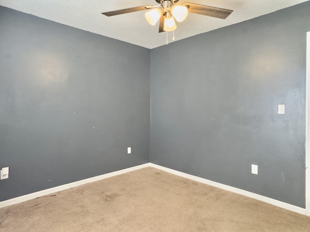 carpeted spare room featuring ceiling fan and baseboards