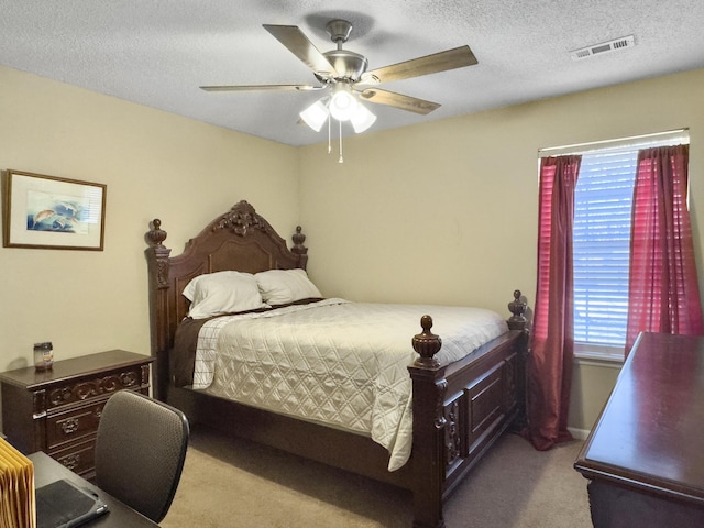 bedroom with a ceiling fan, carpet, visible vents, and a textured ceiling