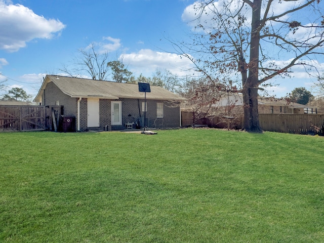 back of property featuring a yard, brick siding, and a fenced backyard