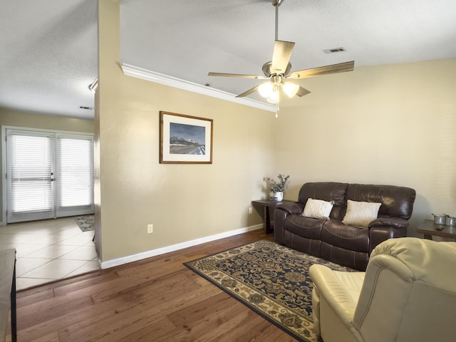 living room with baseboards, visible vents, a ceiling fan, wood finished floors, and a textured ceiling