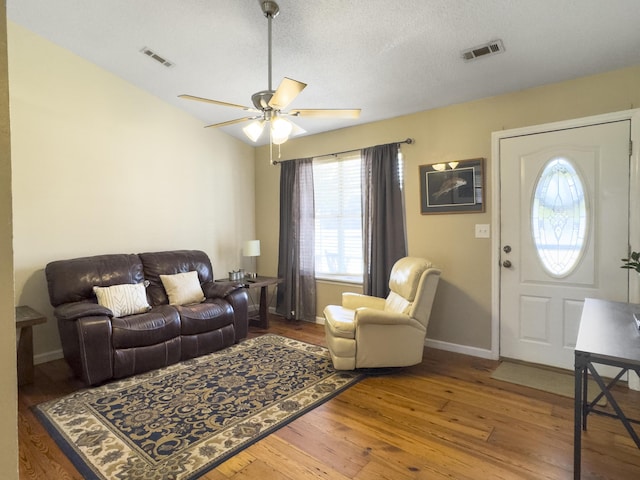 living room featuring wood-type flooring, visible vents, ceiling fan, and baseboards