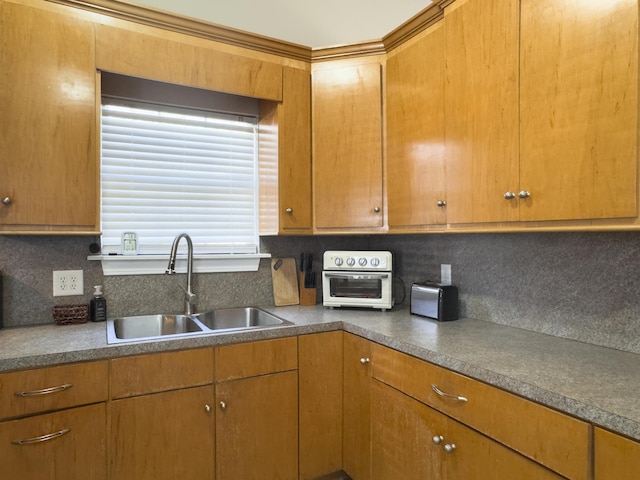 kitchen with tasteful backsplash, a toaster, brown cabinets, and a sink