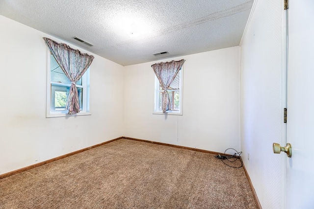 carpeted empty room featuring a textured ceiling, visible vents, and baseboards