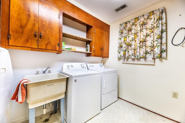 clothes washing area featuring washer and dryer, visible vents, cabinet space, and baseboards