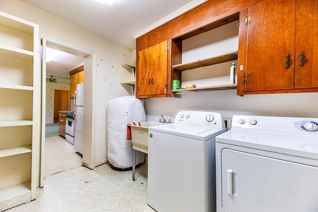 laundry room featuring washer and dryer, light floors, cabinet space, and a sink