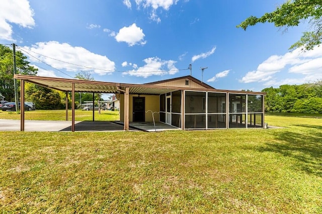 back of property featuring a carport, a sunroom, and a lawn