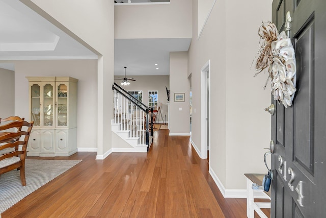 foyer entrance with stairs, baseboards, and wood finished floors