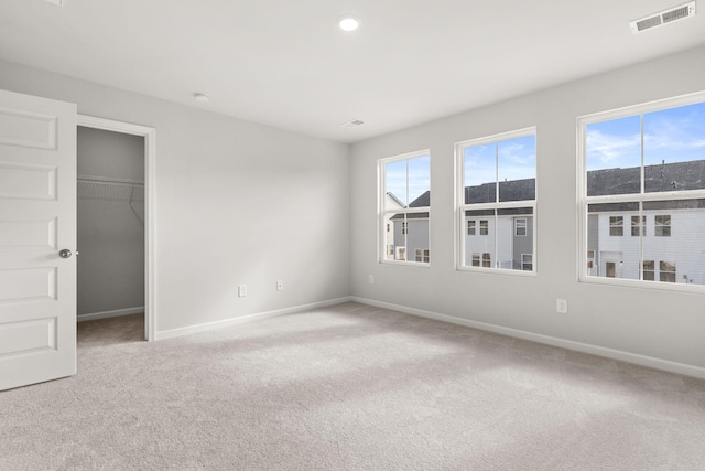 unfurnished bedroom with a walk in closet, light carpet, and a closet