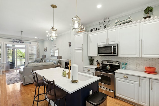 kitchen featuring white cabinets, pendant lighting, light wood-type flooring, and stainless steel appliances