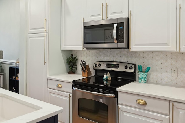 kitchen featuring decorative backsplash, appliances with stainless steel finishes, light stone countertops, sink, and white cabinets