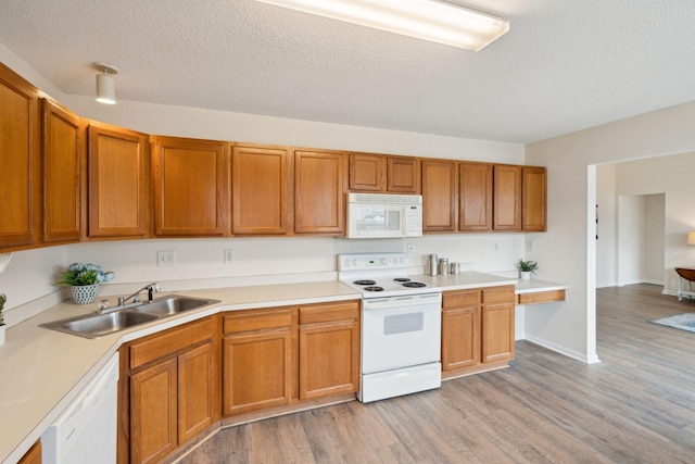 kitchen with light wood-type flooring, a textured ceiling, white appliances, and sink