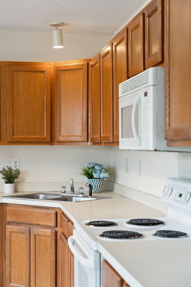 kitchen with sink, white appliances, and a textured ceiling