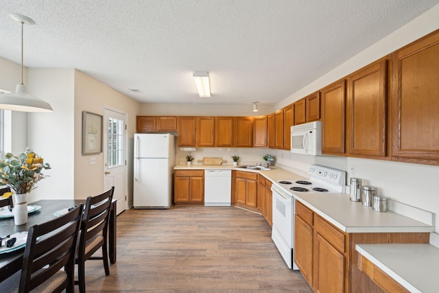 kitchen featuring sink, hanging light fixtures, light hardwood / wood-style flooring, a textured ceiling, and white appliances