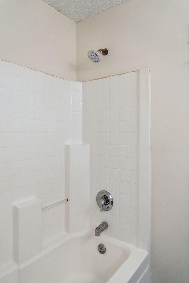 bathroom with a textured ceiling and shower / washtub combination