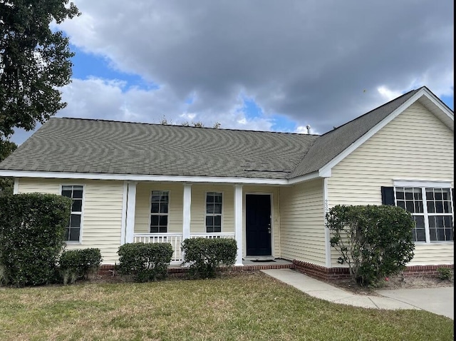 ranch-style house featuring covered porch and a front yard