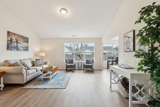 living room with a textured ceiling, vaulted ceiling, and dark wood-type flooring