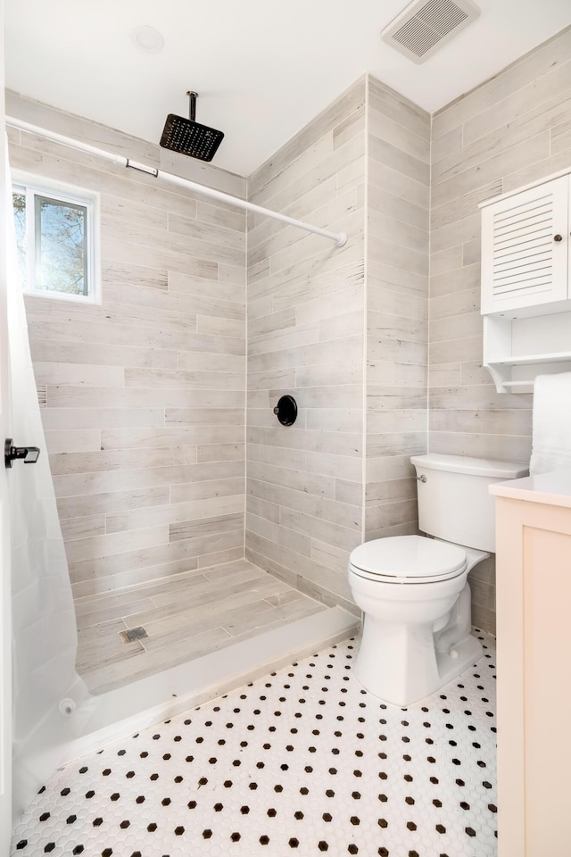 bathroom featuring tile patterned floors, toilet, and tiled shower