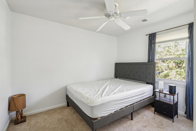 bedroom featuring a ceiling fan, light colored carpet, visible vents, and baseboards