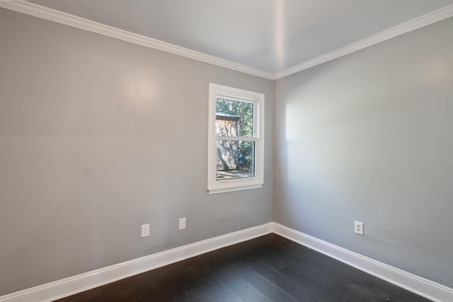 spare room featuring dark wood-style floors, ornamental molding, and baseboards