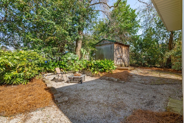 view of yard with an outdoor structure, a fire pit, and a storage unit