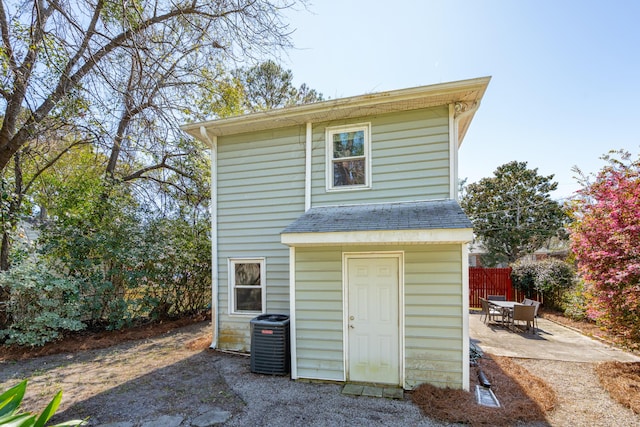 view of outdoor structure with central AC and fence