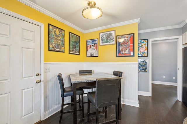 dining space with ornamental molding, wainscoting, wood finished floors, and baseboards