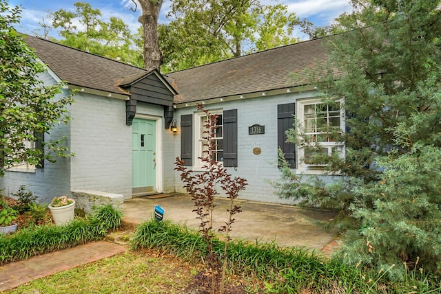 view of front of home with a shingled roof and brick siding