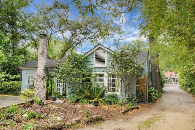 view of front of house with a shingled roof and a chimney