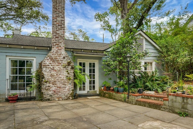 rear view of property with a patio, a shingled roof, and a chimney