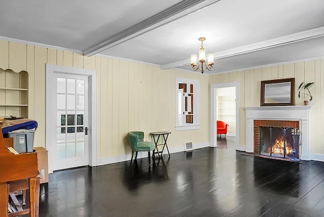 living area with visible vents, a chandelier, wood finished floors, a fireplace, and beam ceiling