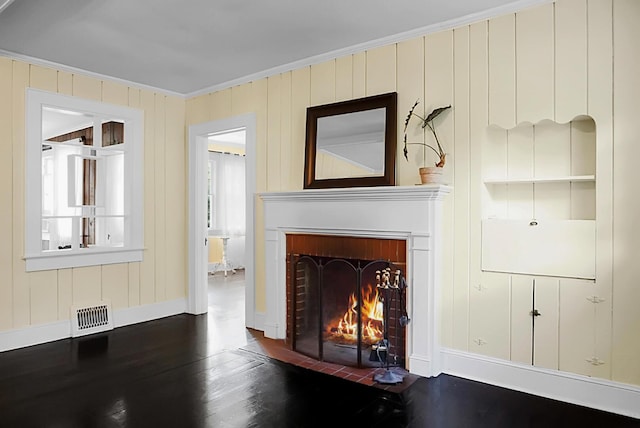 unfurnished living room with wood finished floors, visible vents, a fireplace, crown molding, and baseboards
