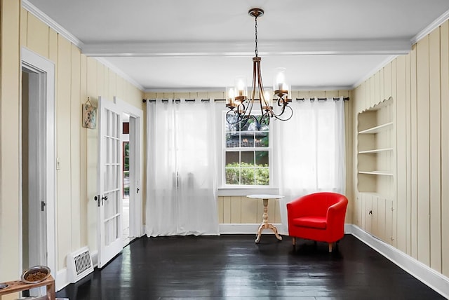living area with an inviting chandelier, hardwood / wood-style floors, visible vents, wooden walls, and ornamental molding