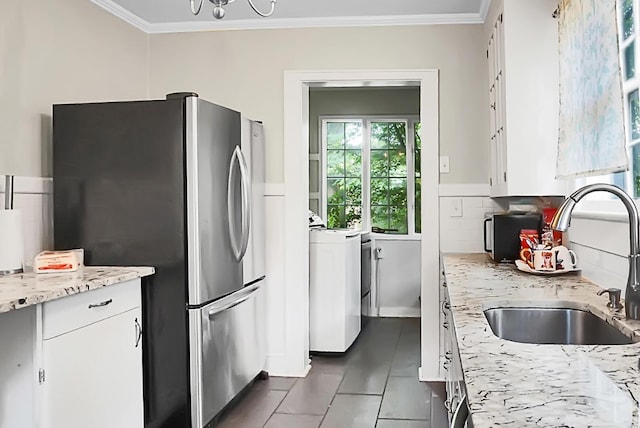 kitchen featuring a sink, freestanding refrigerator, ornamental molding, and washer / clothes dryer