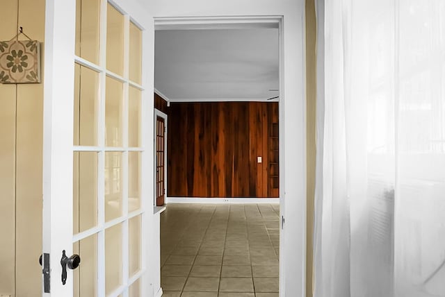 hall featuring crown molding, tile patterned floors, and wood walls