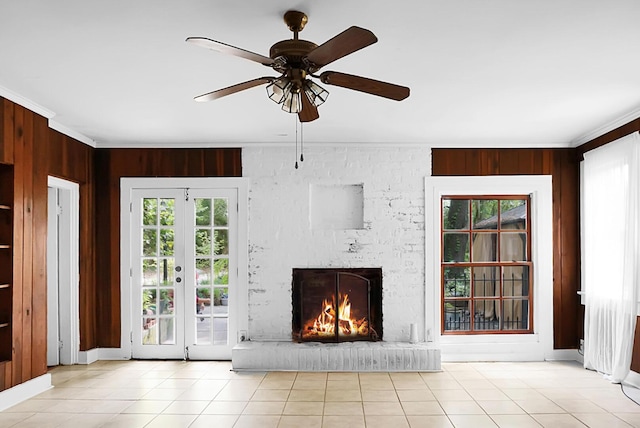 unfurnished living room with ornamental molding, a brick fireplace, a ceiling fan, and wood walls
