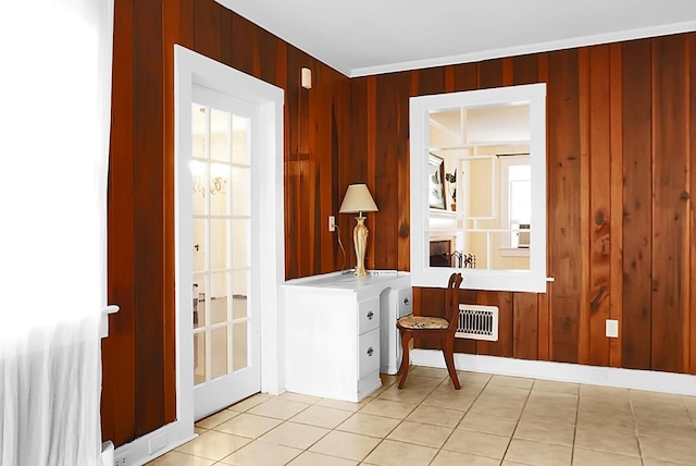 entrance foyer with light tile patterned floors, wooden walls, and ornamental molding