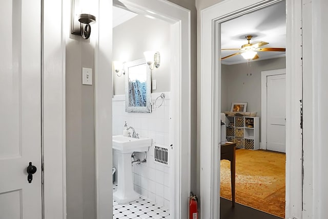 bathroom featuring tile walls, a ceiling fan, and a sink