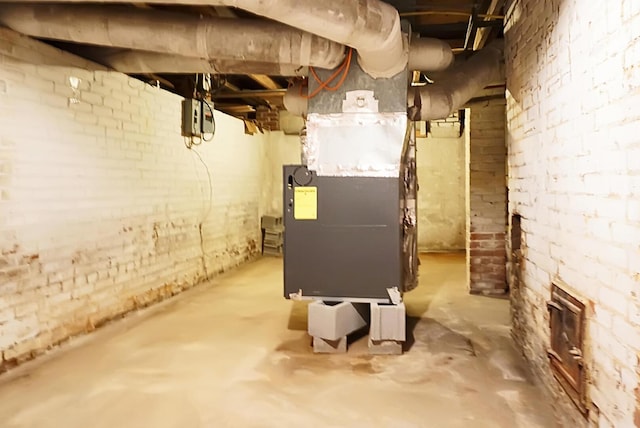 unfinished basement with brick wall and heating unit