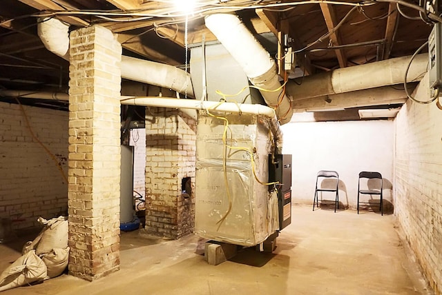 unfinished basement with brick wall, heating unit, and gas water heater