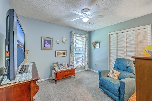 living area with baseboards, visible vents, carpet floors, and a ceiling fan