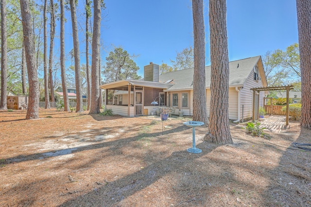 view of front of home with roof with shingles, a sunroom, fence, and a chimney