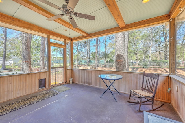 unfurnished sunroom featuring beamed ceiling and ceiling fan