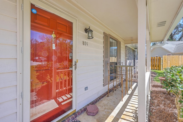 doorway to property featuring fence and a porch