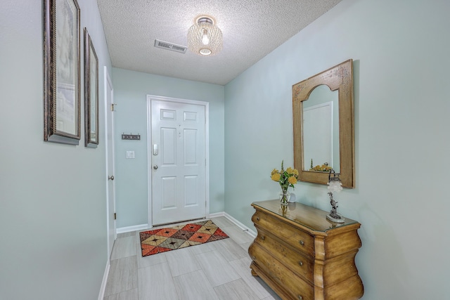 entryway featuring a textured ceiling, baseboards, and visible vents